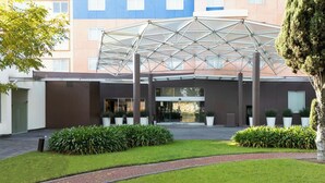 Un edificio moderno con un atrio de vidrio, un sendero de ladrillo y follaje bien cuidado.