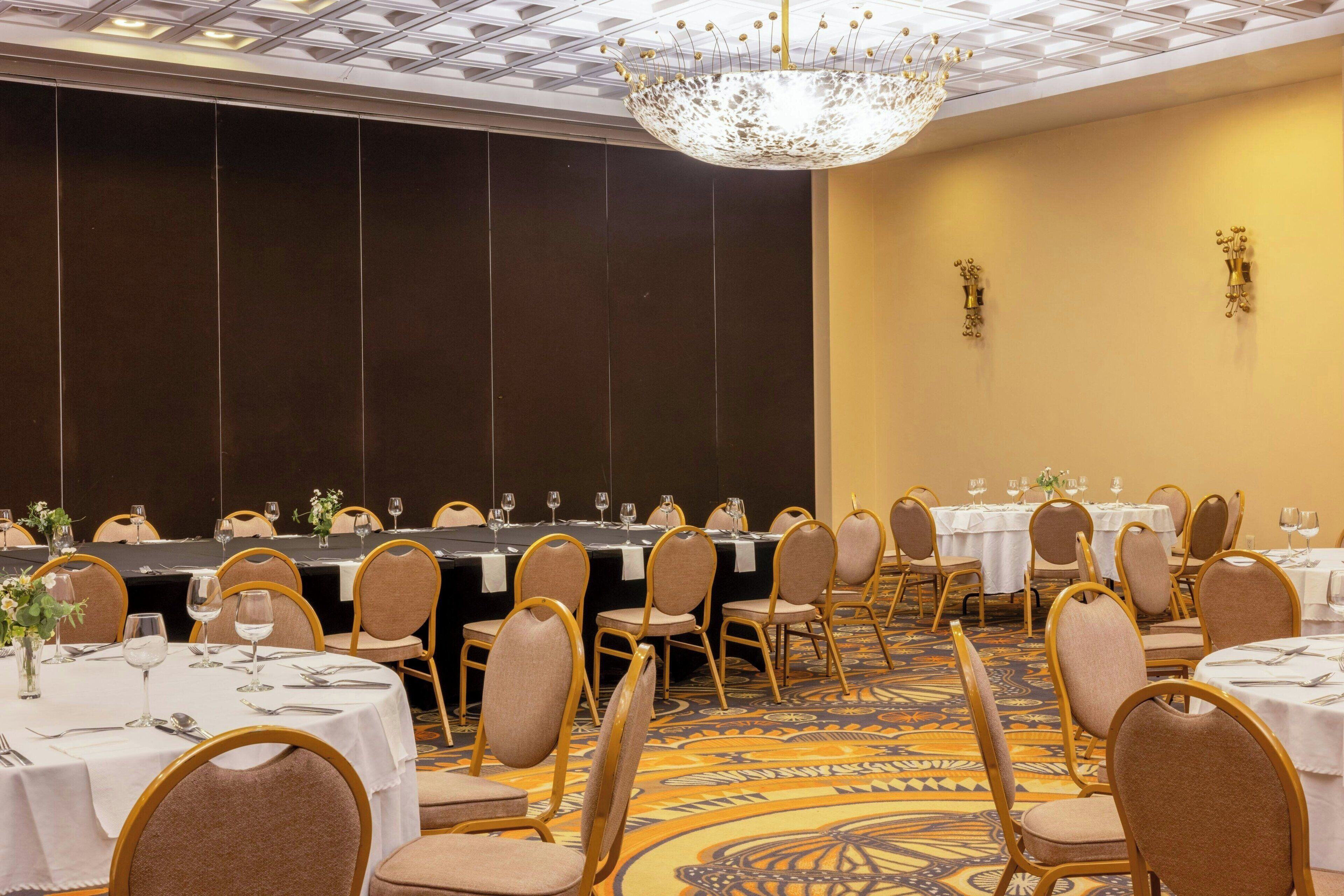 A conference room with round tables, chairs, and a chandelier.