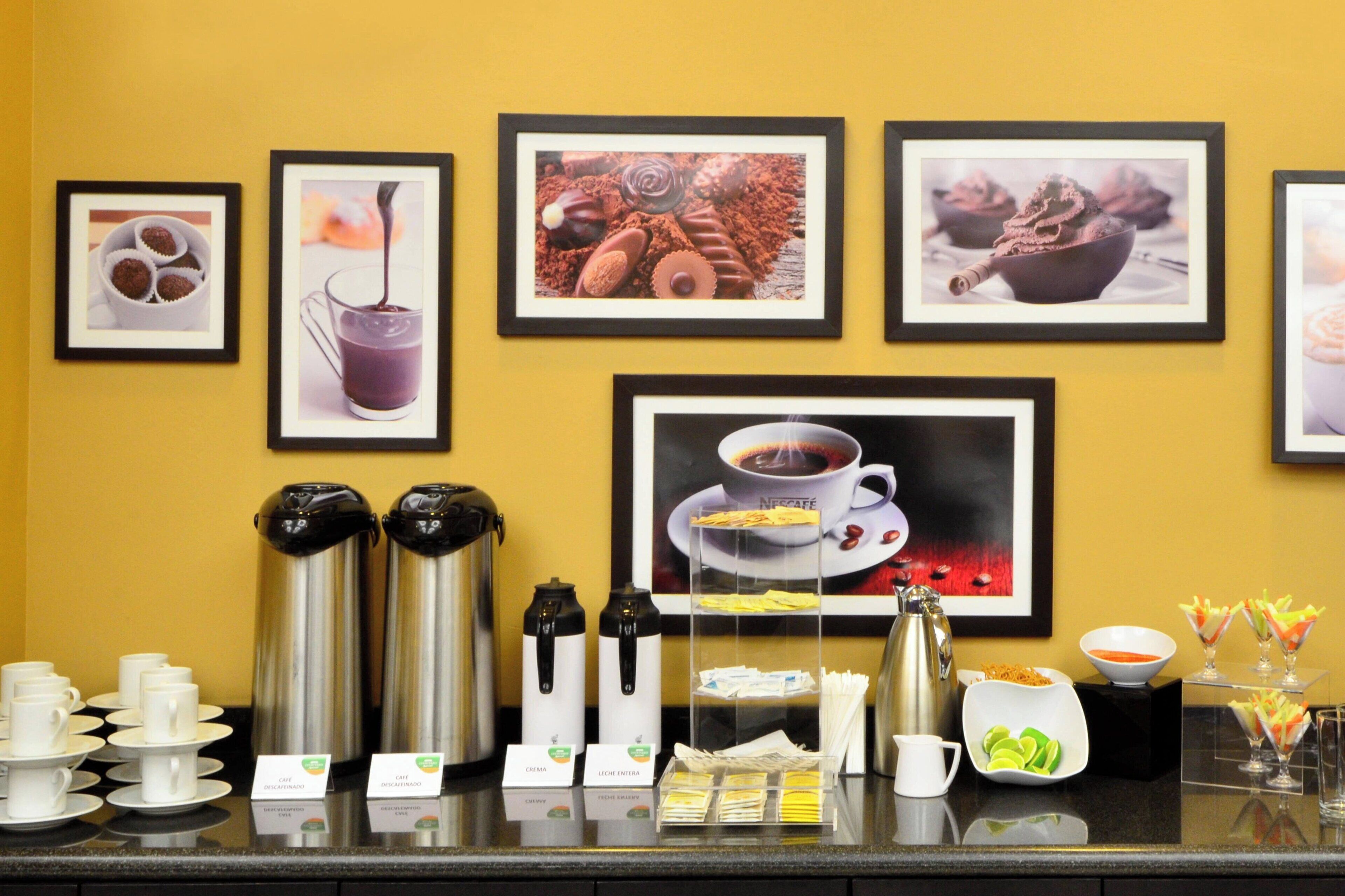 A coffee station with various coffee options, a coffee machine, and a display of coffee cups and saucers.