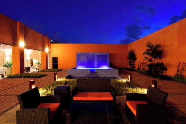 An outdoor seating area with wicker furniture and a central water feature. - Courtyard Toluca Tollocan (Toluca)