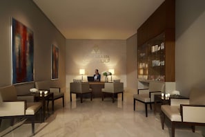 A reception area with a receptionist desk, two chairs, a small table with a vase of flowers, and a bookshelf.