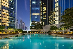 A swimming pool with lounge chairs and a city skyline in the background.
