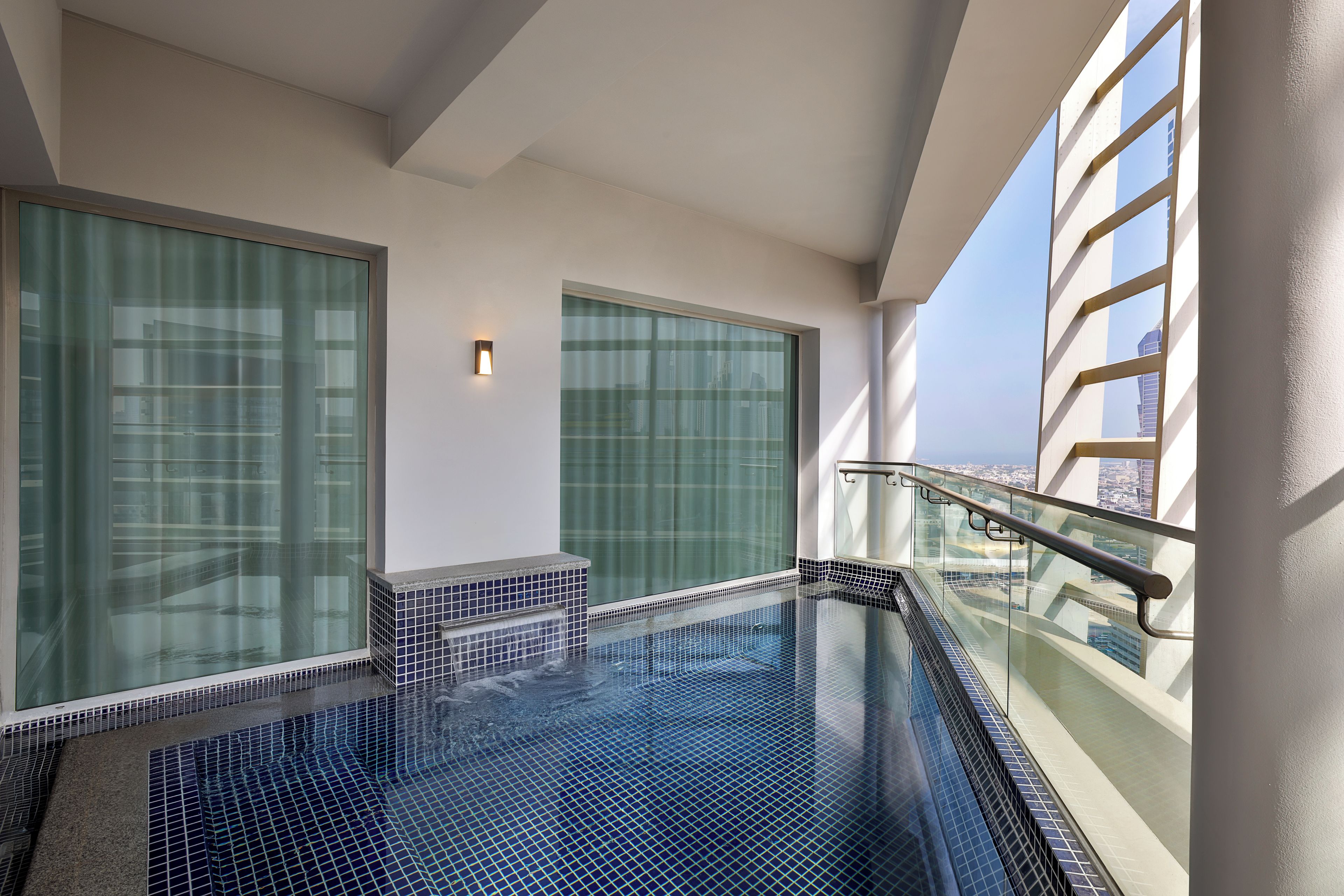 Piscina interior moderna com paredes de vidro e vista para a cidade.