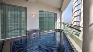 Piscina interior moderna com paredes de vidro e vista para a cidade.