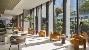 Un hall d’entrée spacieux, doté de meubles modernes, de grandes fenêtres et de plantes d’intérieur.