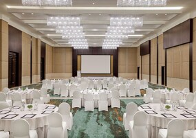 A large conference room with round tables, white chairs, and chandeliers.