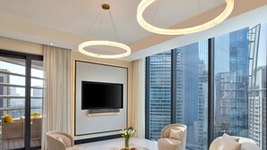 Un salon moderne doté d’un grand téléviseur à écran plat, de sièges confortables et offrant une vue sur la ville.