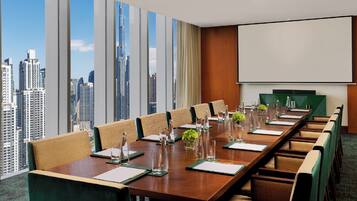 A conference room with a city view, a large table, and a screen.