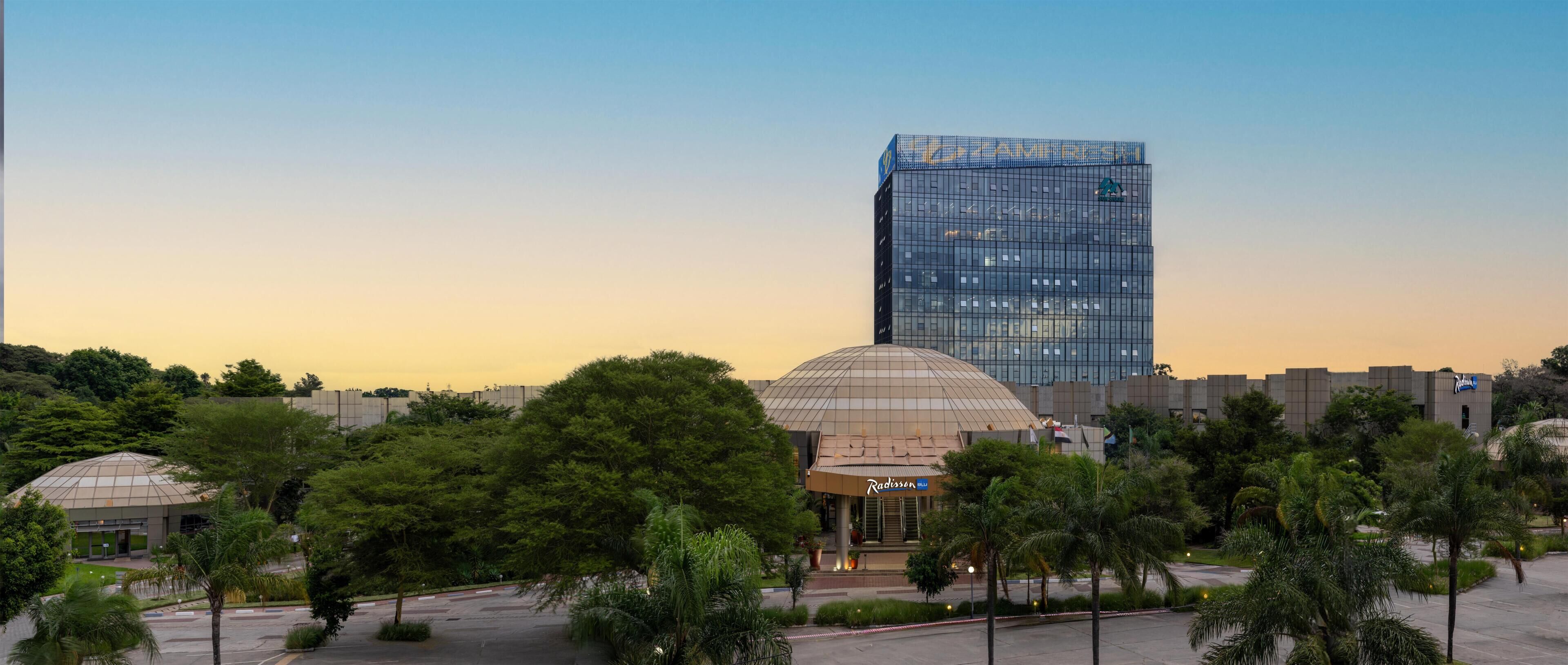 Een modern gebouw met een glazen gevel, een koepelstructuur en een bord met Radisson Blu erop.