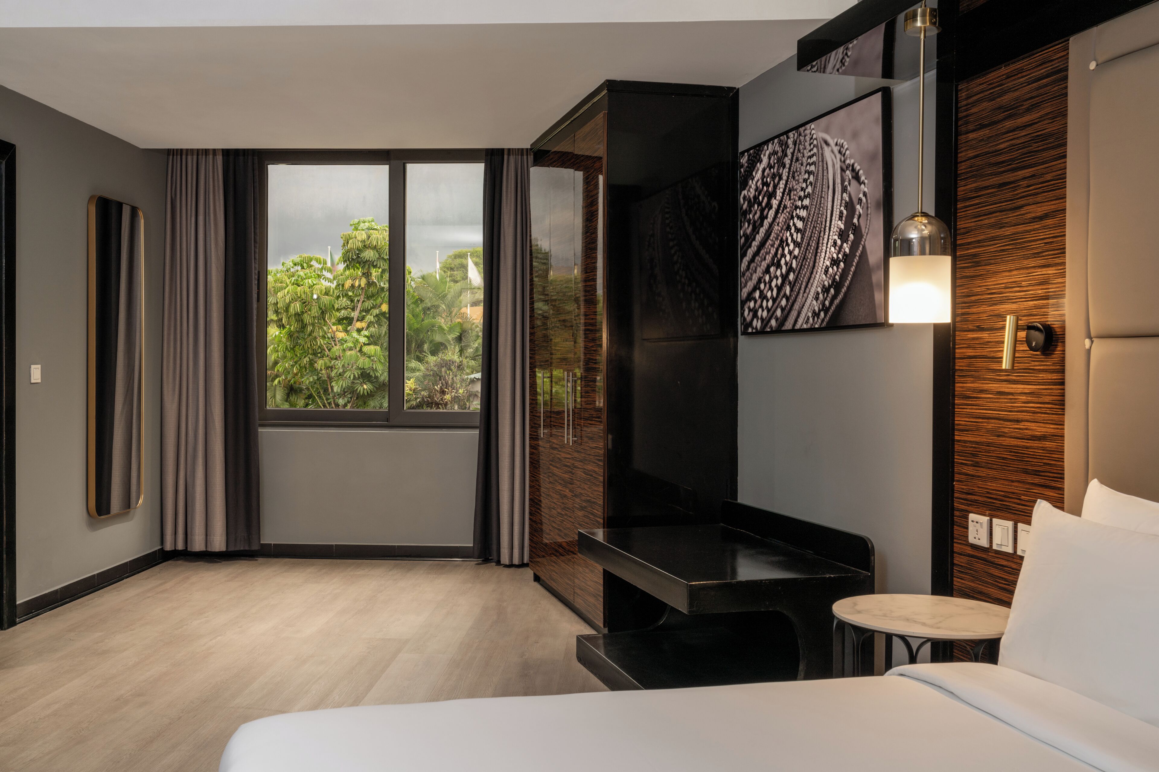 A modern hotel room with a large window, a bed, a small table, and a TV.