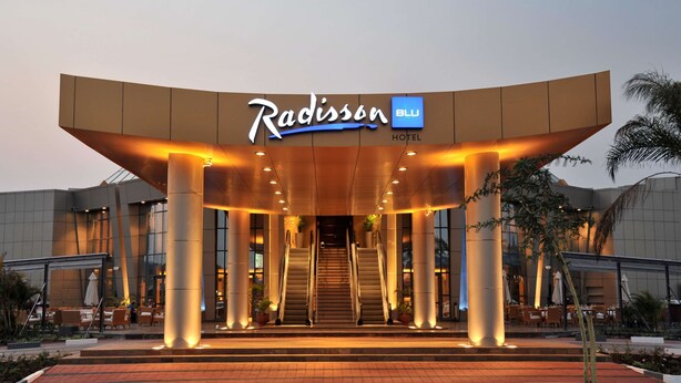 The Radisson Hotel entrance with a modern design, featuring a prominent sign and a staircase leading to the lobby. - Radisson Blu Hotel Lusaka (Lusaka)