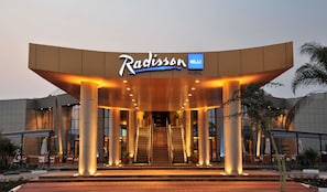 Entrada del Hotel Radisson con diseño moderno, destacando un letrero llamativo y una escalera que conduce al vestíbulo.