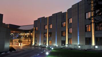 Un edificio moderno con fachada de vidrio, múltiples ventanas y un área de entrada bien iluminada.