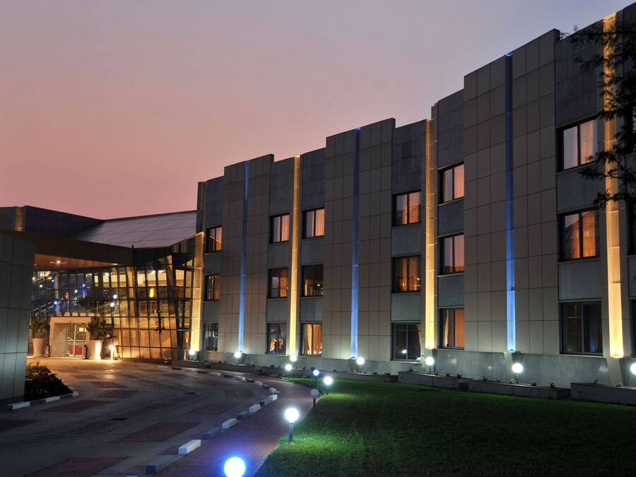 Un edificio moderno con fachada de vidrio, múltiples ventanas y un área de entrada bien iluminada.