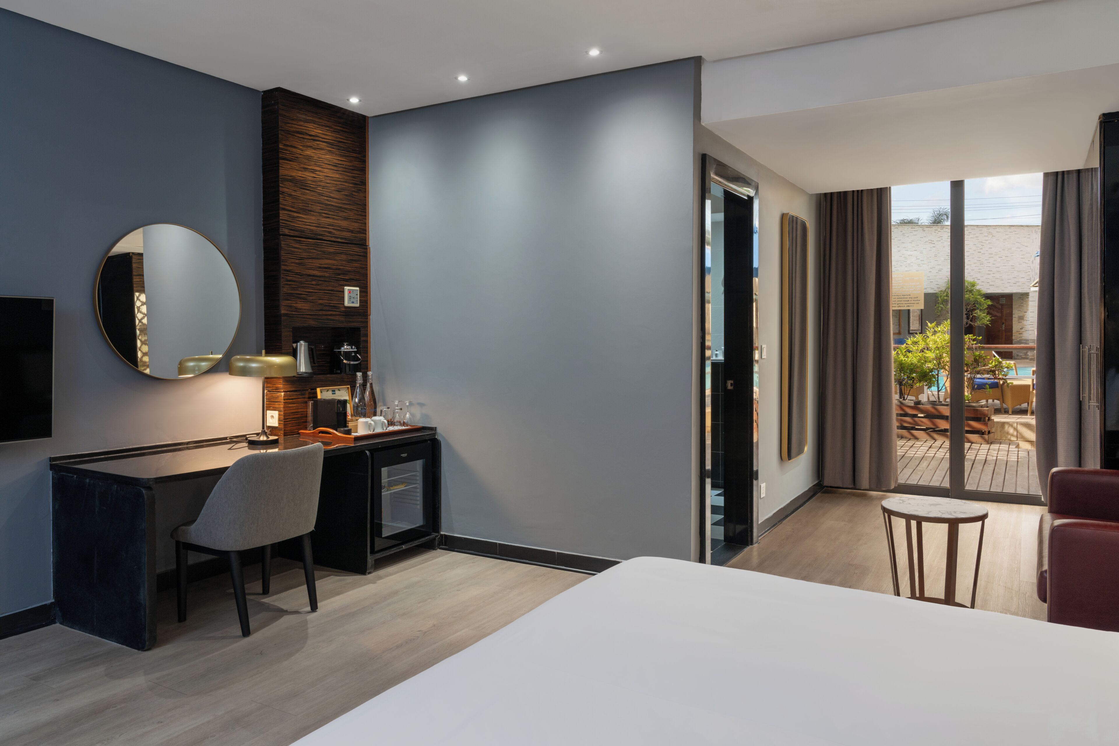 Una habitación de hotel moderna con cama, escritorio, silla y un gran ventanal con vistas al exterior.
