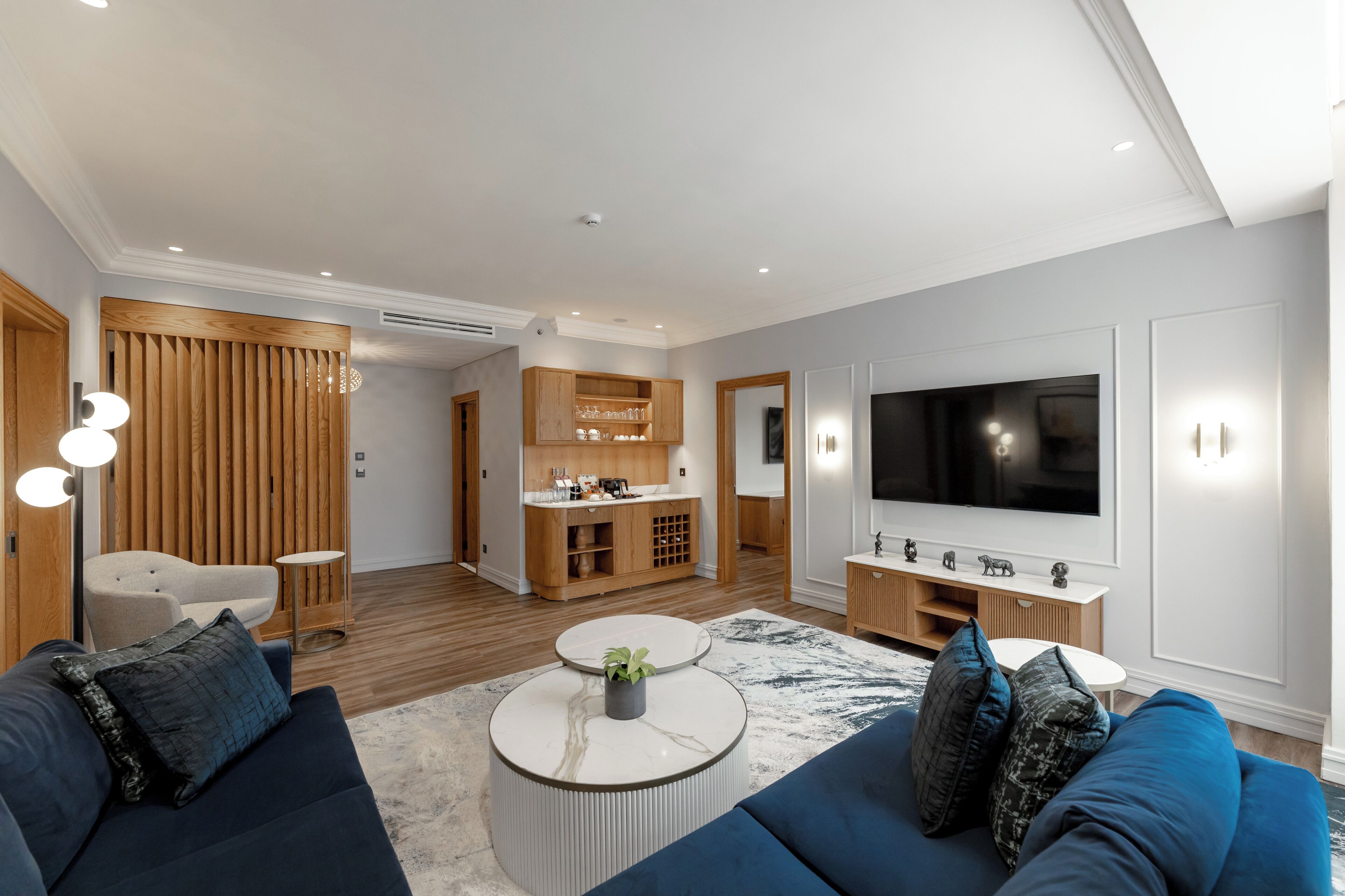 A modern living room with a sofa, coffee table, TV, and wooden cabinetry.