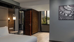 A modern hotel room with a large bed, a small table, a wardrobe, and a large window offering a view of greenery. - Radisson Blu Hotel Lusaka (Lusaka)