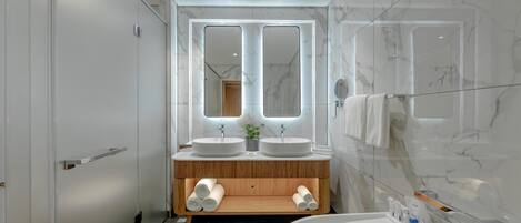 A modern bathroom with two sinks, a large mirror, and a glass-enclosed shower.