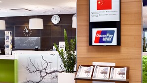 A reception desk with a clock, a UnionPay sign, and a display of magazines. - Scandic Siuntio (Siuntio)