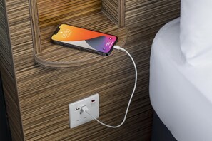 A smartphone charging on a wooden surface near a power outlet. - Travelodge Darlington (Darlington)