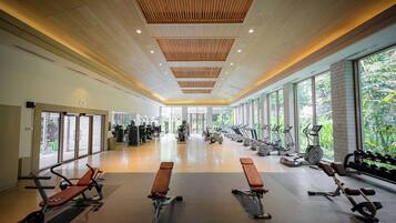 Un gimnasio amplio con diversos equipos de ejercicio, ventanas grandes y techo de madera.
