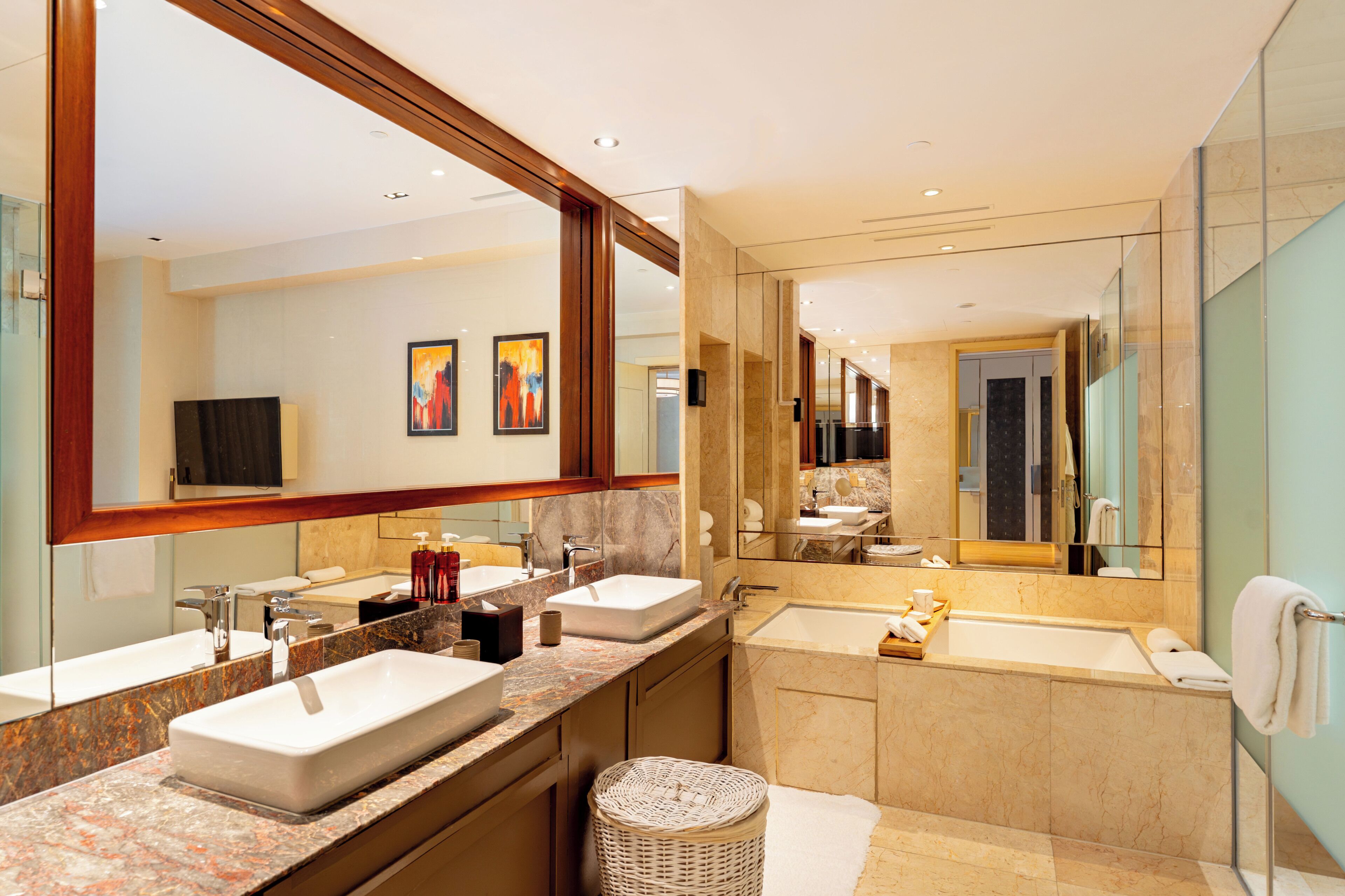 A modern bathroom with two sinks, a bathtub, and a large mirror.