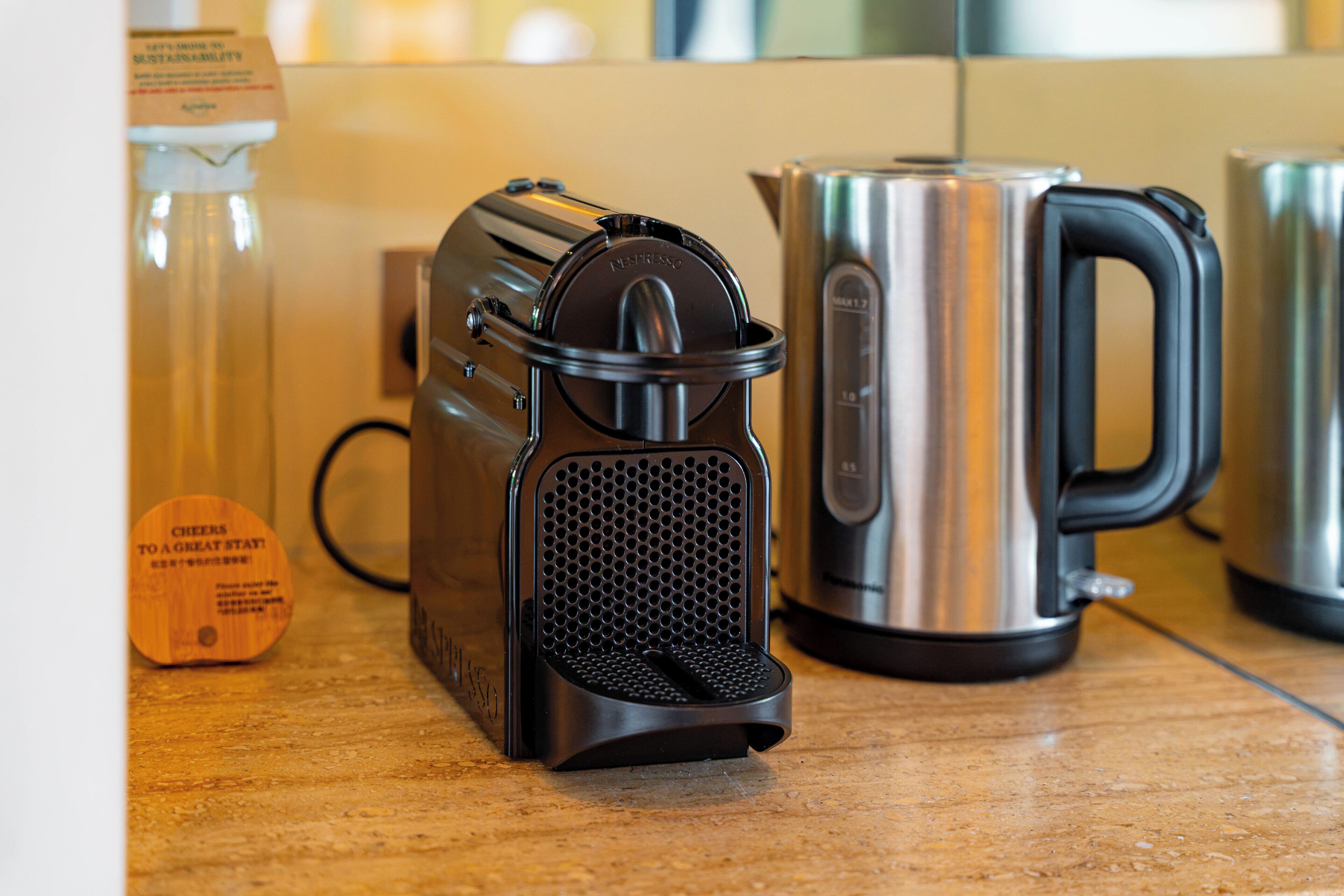 Une machine à café dotée d’un réservoir d’eau et d’une cafetière en acier inoxydable, posée sur un plan de travail.