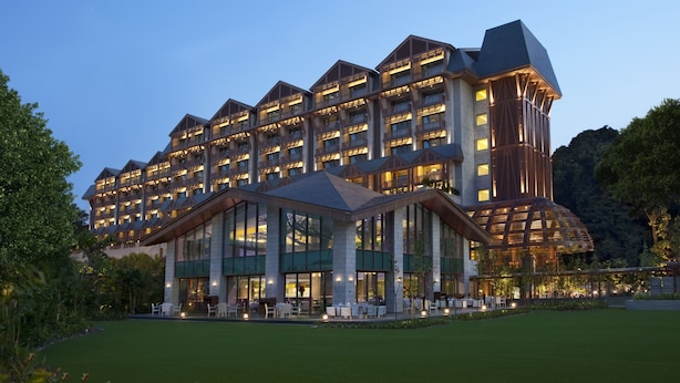 A multi-story hotel with a modern architectural design, featuring a central courtyard with outdoor seating and a well-maintained lawn. - Resorts World Sentosa - Equarius Hotel (Singapore)