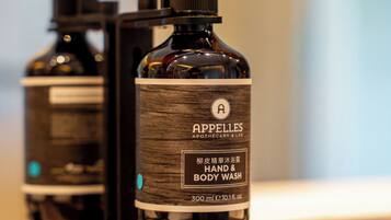 A bottle of hand and body wash with a pump dispenser, placed on a surface with a blurred background.