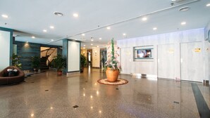 A modern lobby with a polished floor, a staircase, potted plants, and a reception area. - Hotel Continental (George Town)