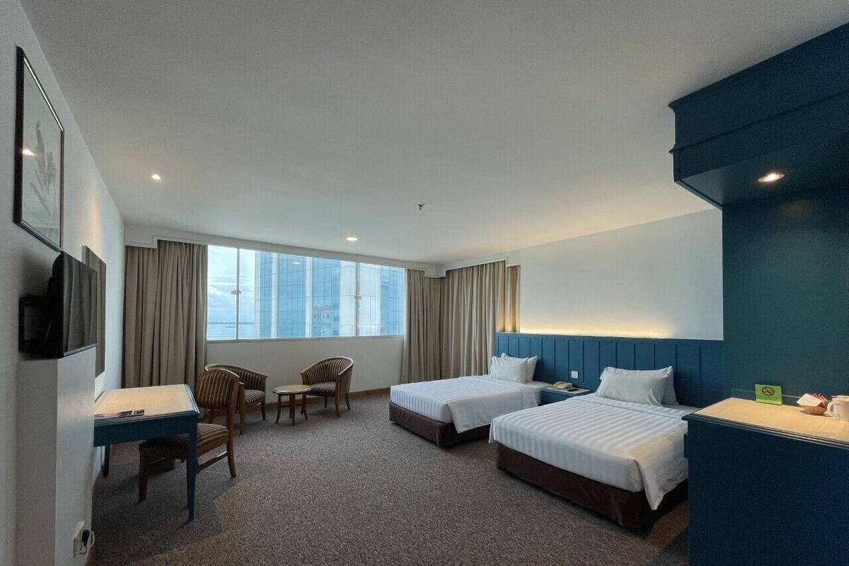 Una habitación de hotel con dos camas, un escritorio, una silla y un televisor.