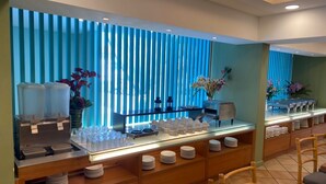 A buffet setup with a beverage station, glassware, and plates. - Hotel Continental (George Town)