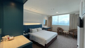 A hotel room with a large bed, a desk, two chairs, a TV, and a window with a view. - Hotel Continental (George Town)