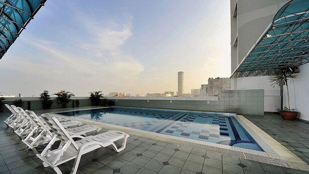 A rooftop pool with lounge chairs, a tiled floor, and a cityscape view in the background. - Hotel Continental (George Town)