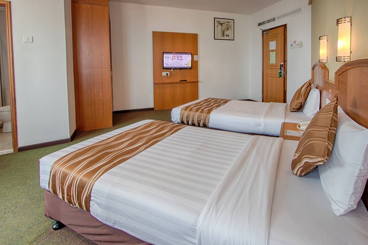 Habitación de hotel con dos camas, un televisor y una puerta de madera.