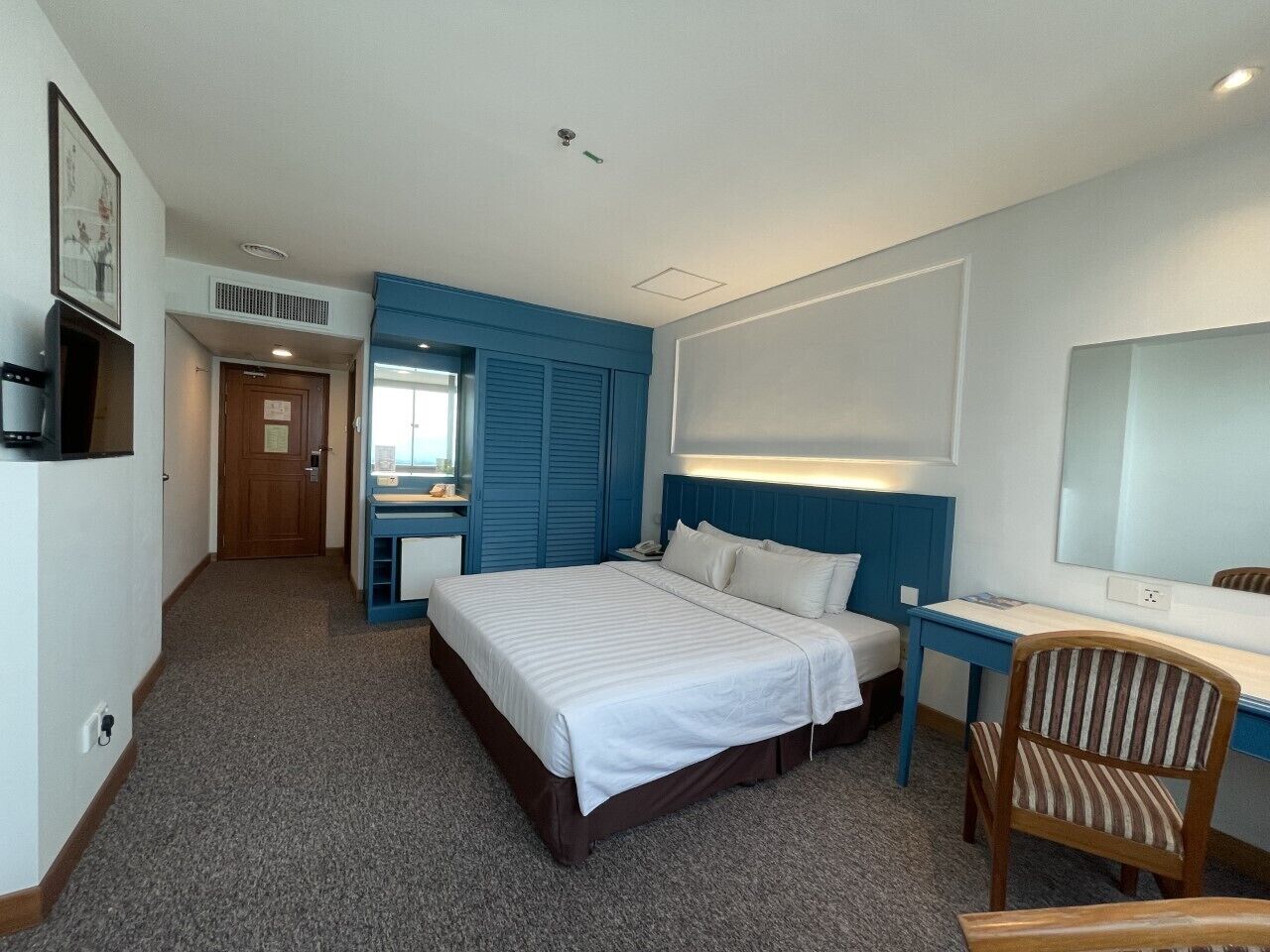 Ein Hotelzimmer mit einem großen Bett, einem Schreibtisch, einem Stuhl und einem Spiegel.