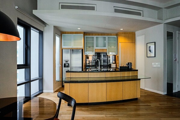 A modern kitchen with a central island, built-in cabinets, and a glass-top dining table.
