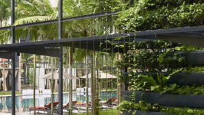 A modern outdoor area with a pool, lounge chairs, and lush greenery. - E&O Residences Kuala Lumpur (Kuala Lumpur)