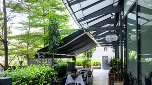 An outdoor dining area with tables and chairs, a canopy, and greenery. - E&O Residences Kuala Lumpur (Kuala Lumpur)
