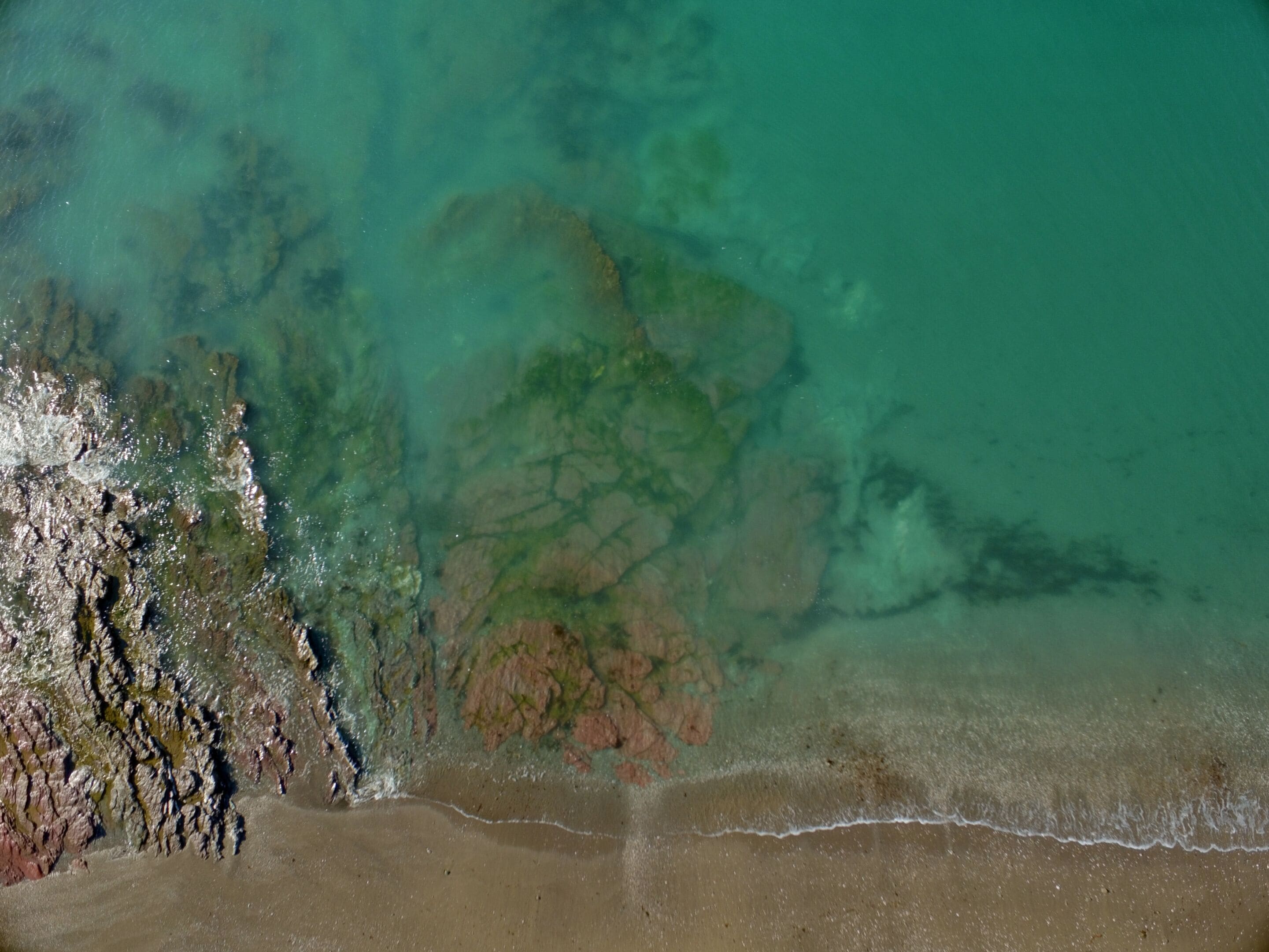 Un paysage côtier avec une plage de sable et des formations rocheuses.