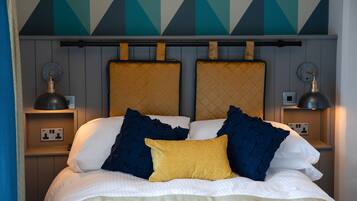 A bed with a headboard, two bedside lamps, and a power outlet on the nightstand.