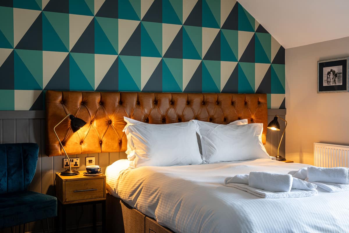 A neatly made bed with white linens, a tufted headboard, and two bedside lamps.
