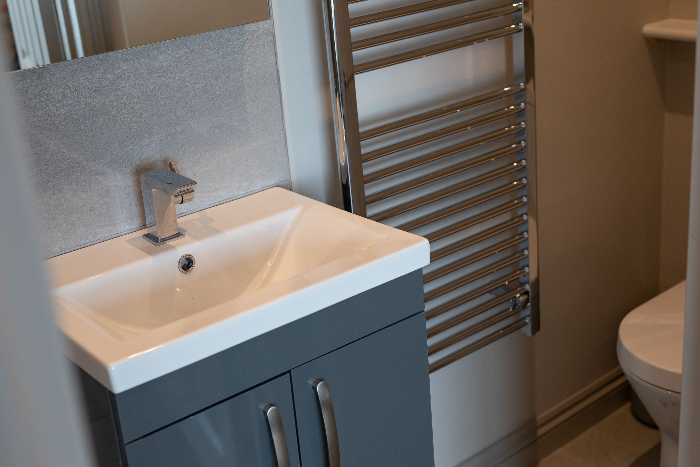 A bathroom with a white sink, a mirror, and a towel rack.