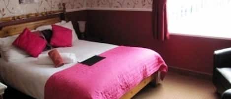 A bedroom with a bed, pillows, a nightstand, and a chair.