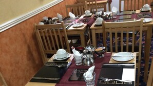 A dining area with wooden tables and chairs, each set with plates, cutlery, and glasses. - The Kingscliff (Blackpool)