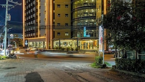Un hotel de varios pisos con diseño moderno, que destaca por su fachada curva de vidrio e iluminación exterior.