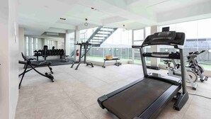 Un gimnasio amplio con cintas de correr, pesas y una escalera que da a un espacio exterior.
