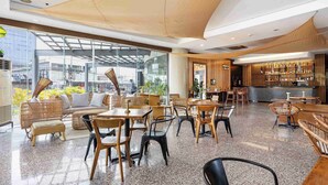Un café espacioso con mobiliario de madera, una zona de bar y amplios ventanales que ofrecen vistas de la ciudad.