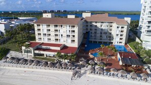 Een hotel met meerdere verdiepingen, een zwembad en een strandgedeelte met parasols.