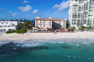 Un hotel sul lungomare con diversi piani, una spiaggia attrezzata con ombrelloni e vista sull'oceano.